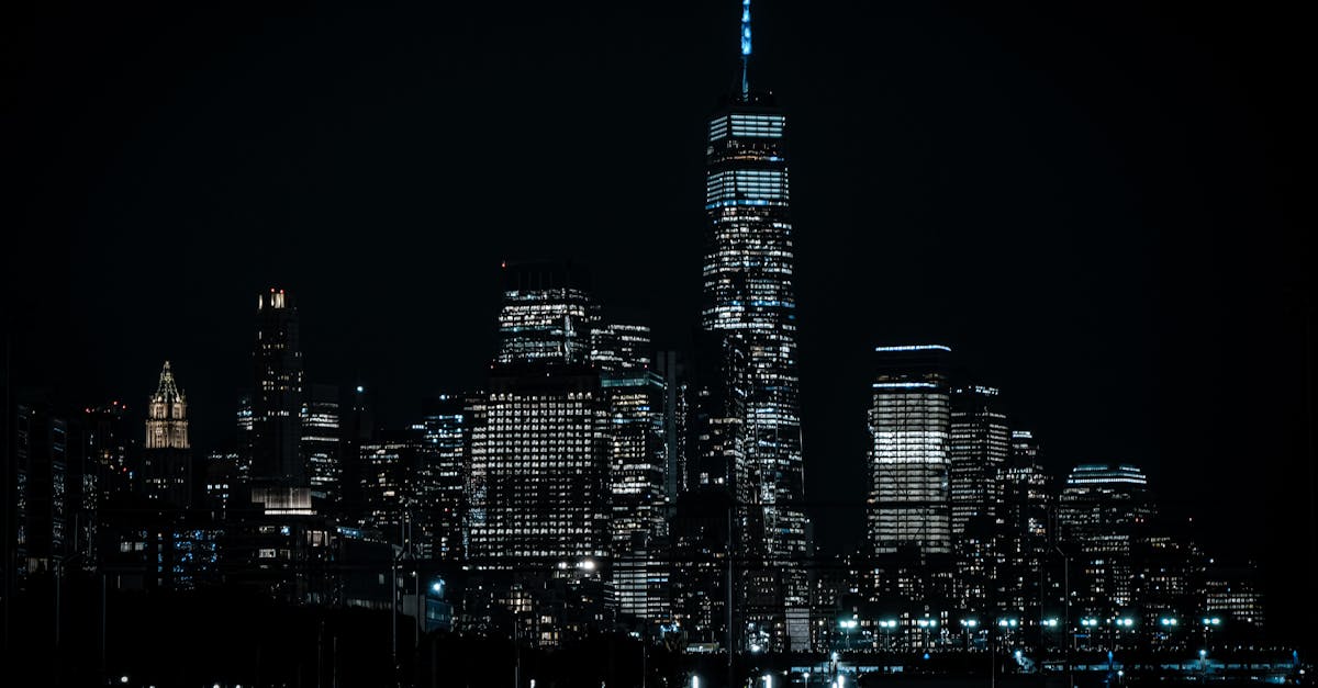 A new dark city skyline rising at night beside the silhouette of an older structure