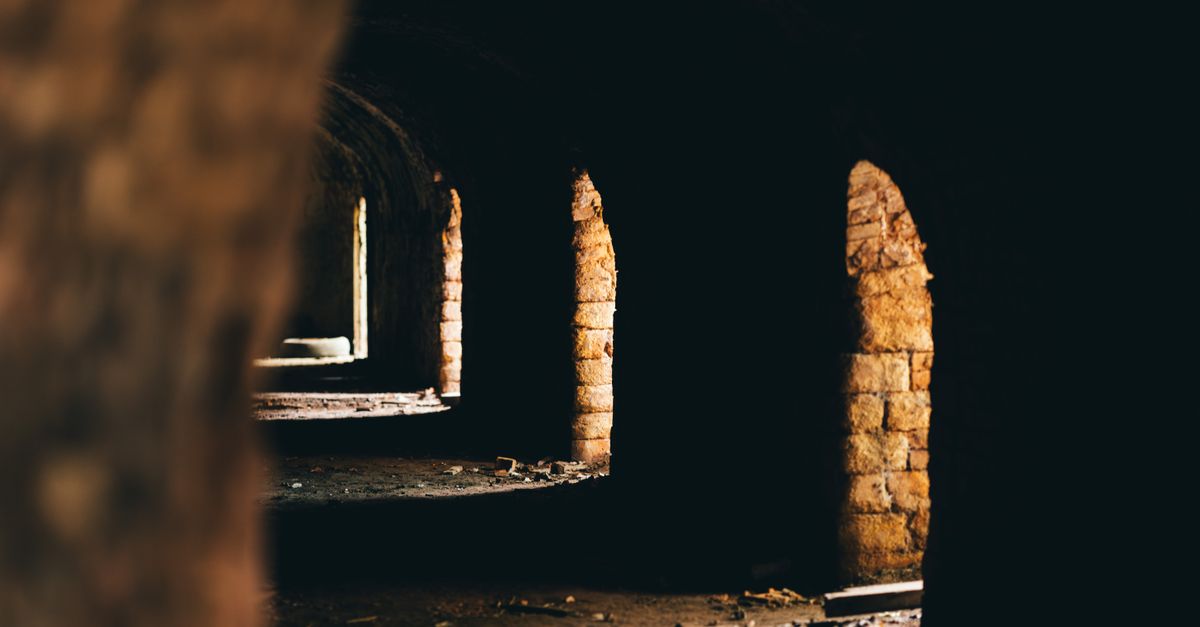 A long dark corridor of thirteen identical stone arches receding into shadow