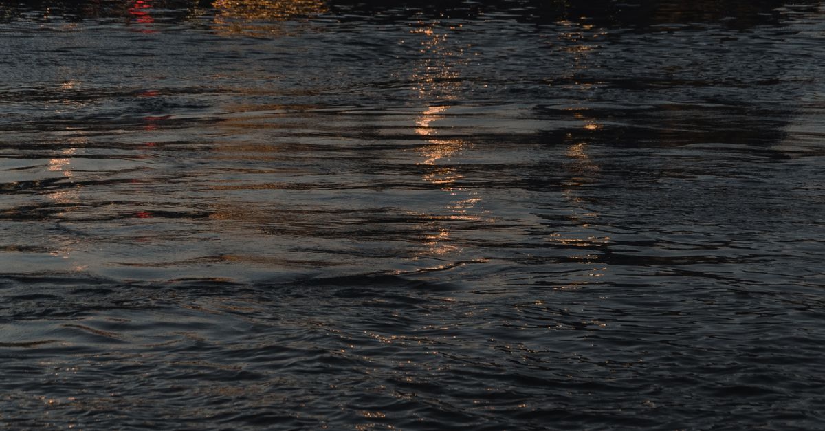 Perfectly still dark water reflecting faint light, composure as a form of power