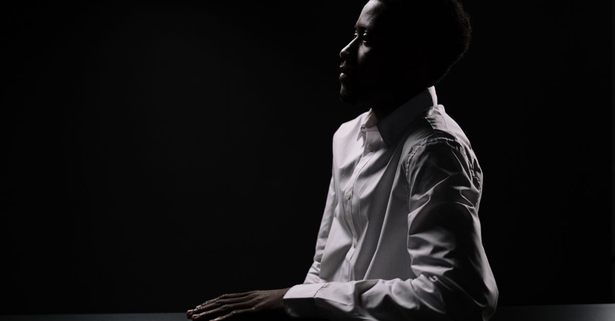A calm portrait half in shadow, the steady inner signal of confidence that needs no audience
