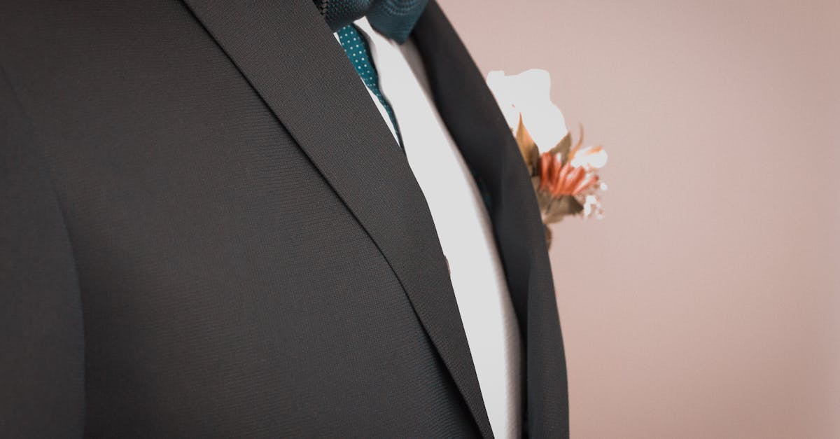 Close detail of a tailored dark jacket lapel and stitching under low gold light