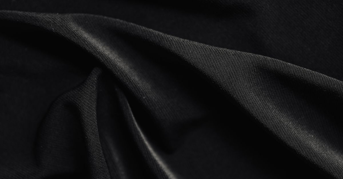 A minimal fold of monochrome cloth in soft shadow with a faint gold edge