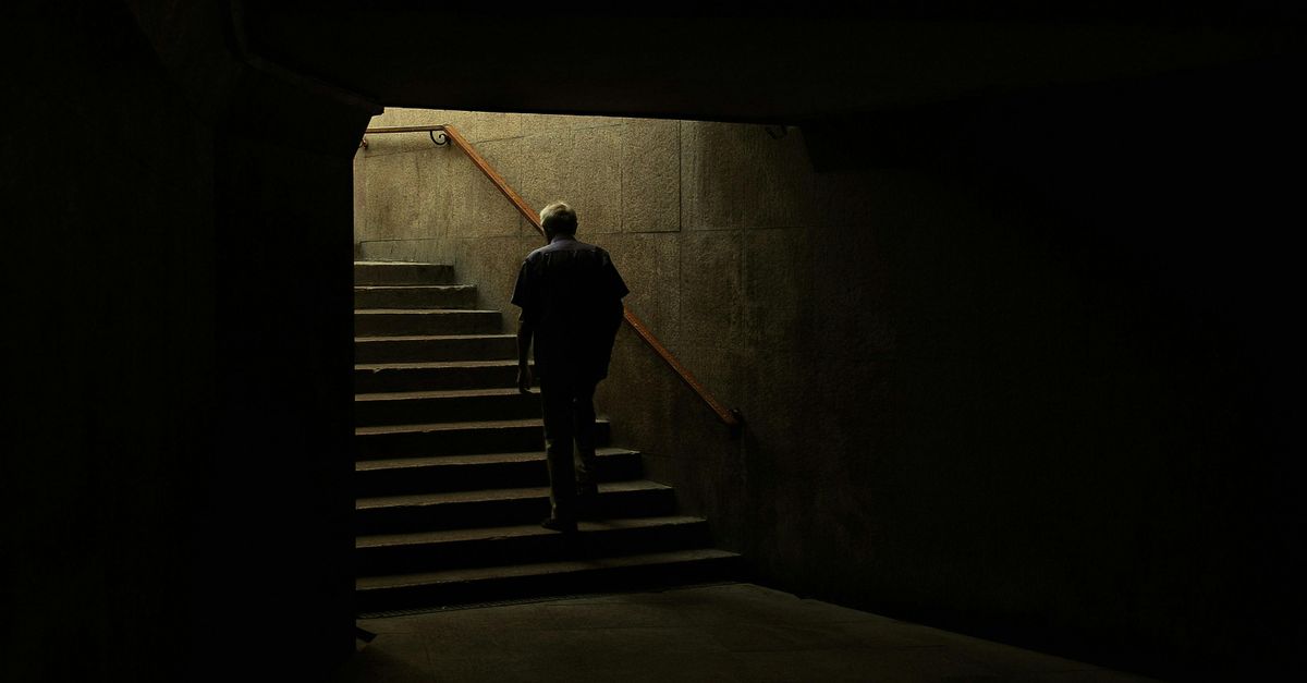 A figure looking inward at a doorway of light, depicting inner mastery preceding outer freedom