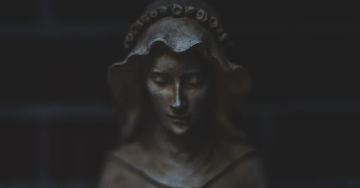 A carved stone statue in low light, the body as the unfakeable standard that records every promise