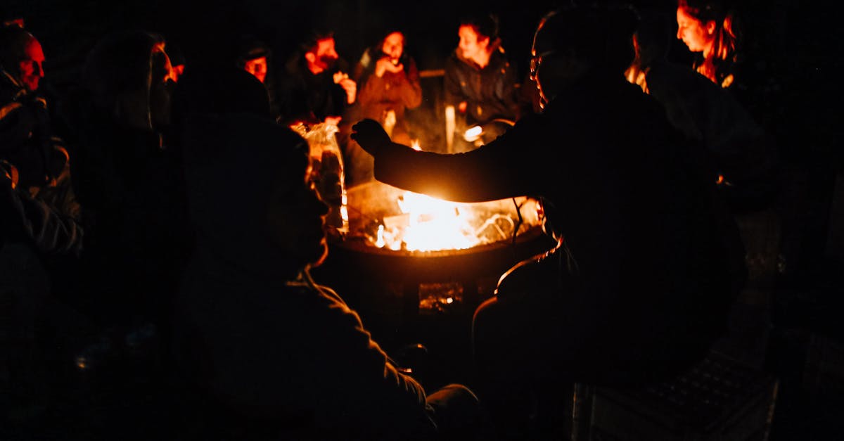 People gathered around a fire at night, faces lit, the dark city behind them